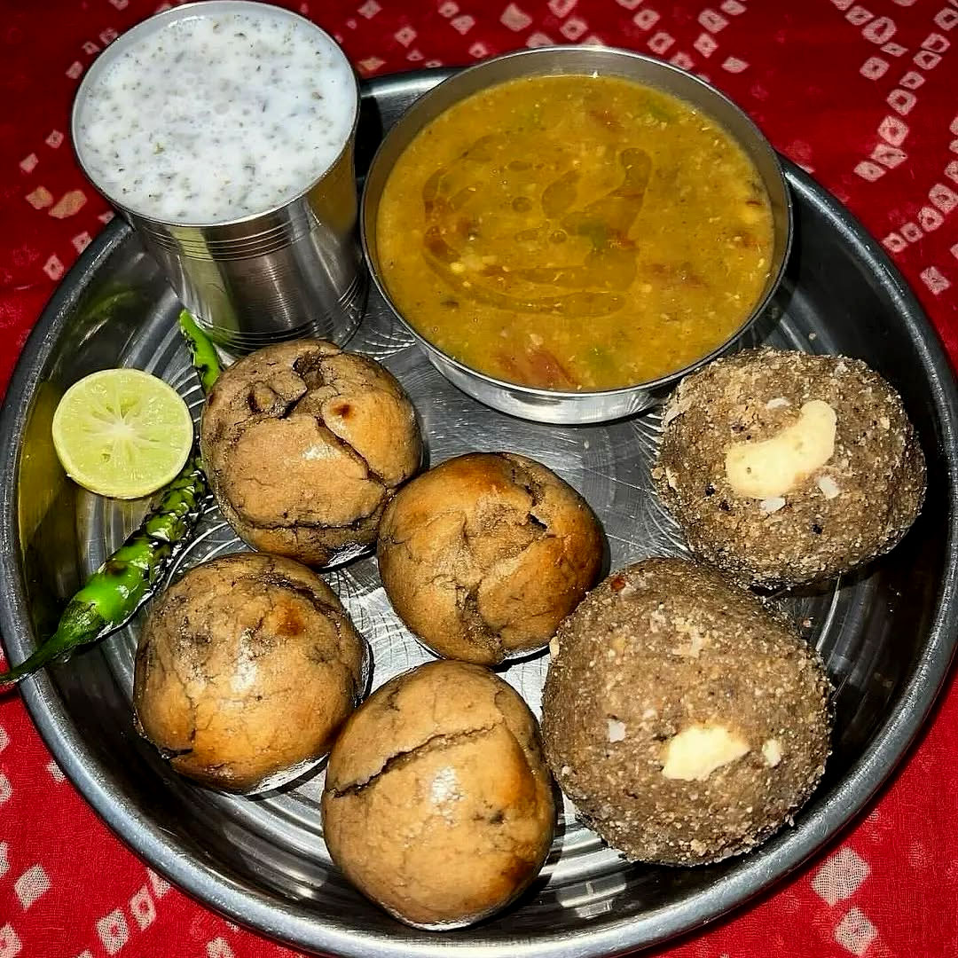TTraditional Rajasthani Daal Bati Churma on a rustic plate with ghee.
